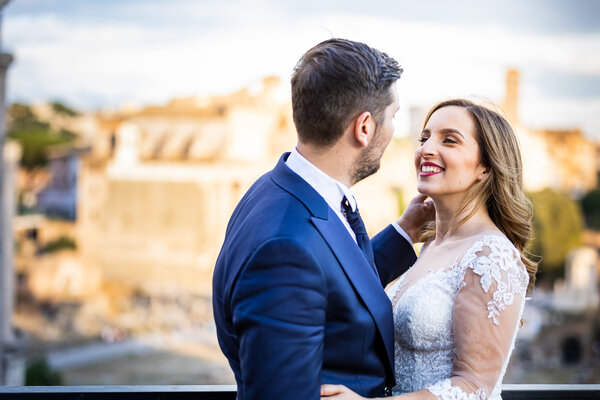 Newly-weds smiling at each other with the Roman Forum in the background at the golden hour