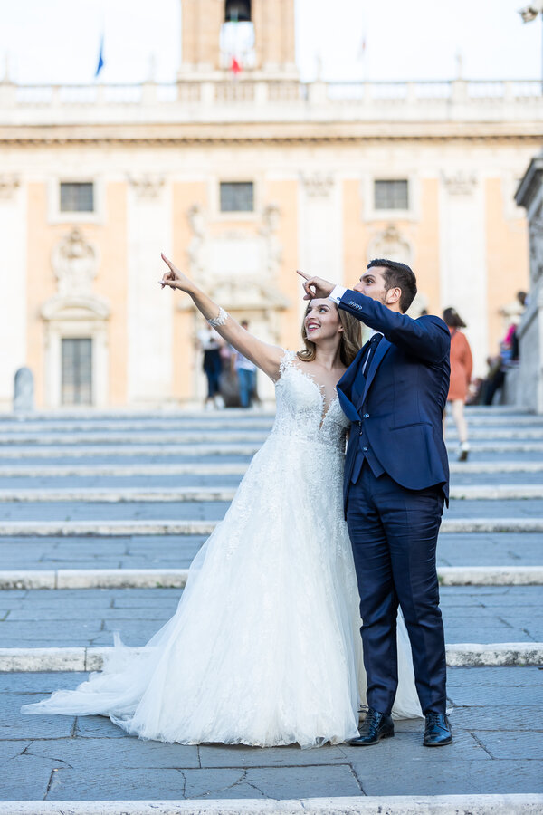 Bride and Groom point to the Vittoriano while on the staircase to the Capitoline Hill