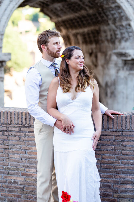 A chamring newly-wed couple posing next to the Septimius Severus Arch during their wedding photo session in Rome