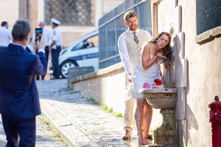 Wedding couple drinking from a typical roman water fountain on the Capitoline Hill in Rome