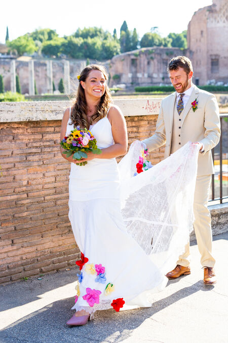 Groom holding the wedding gown train during their wedding photo session in Rome