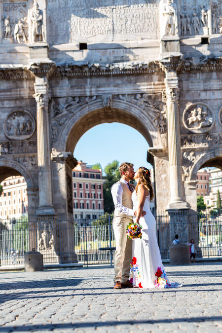 Newly-wed holding each other with the Costantine Arch in the background