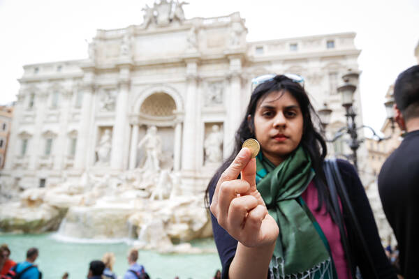 Solo Traveller throws a coin into the Trevi Fountain in Rome