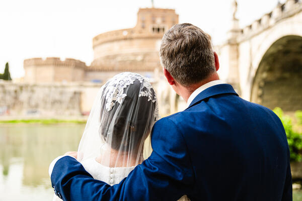 Sposi Novelli couple looking at Castel Sant'Angelo from the Tiber riverbank in Rome