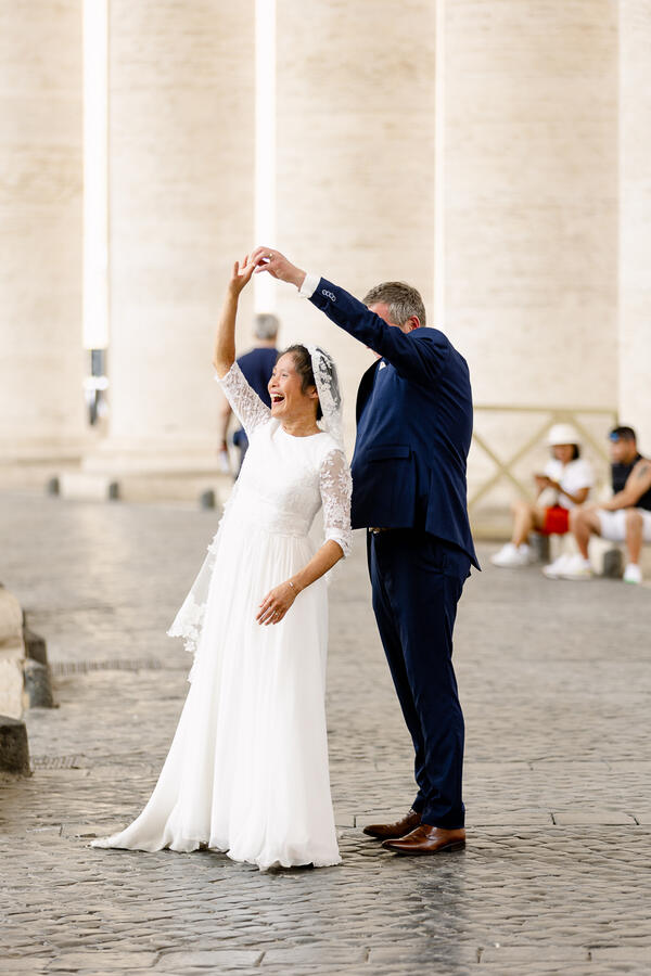 Happy Sposi Novelli couple doing the twirl under the colonnade in Saint Peter's Square in Rome