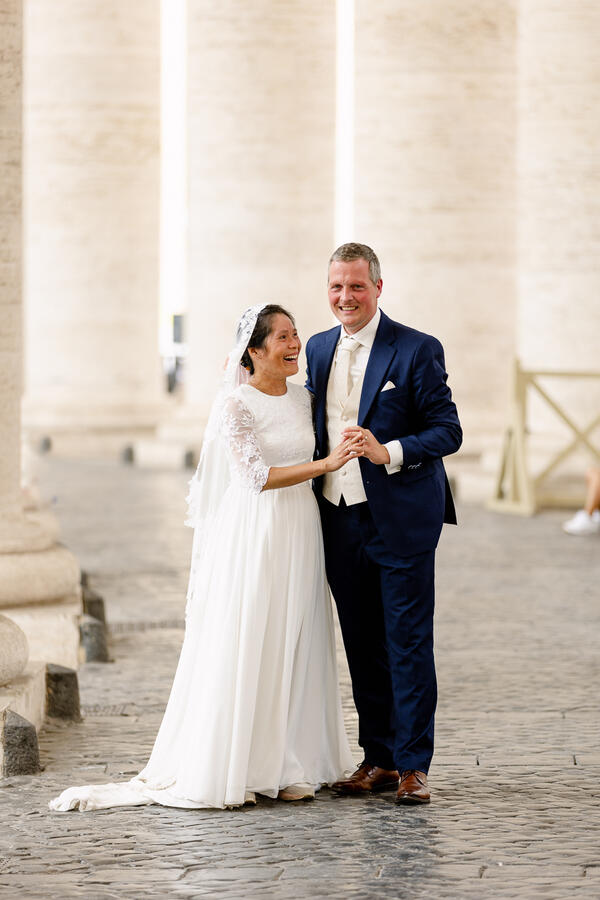 Happy Sposi Novelli couple under the colonnade in Saint Peter's Square in Rome