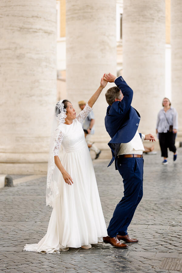 Happy Sposi Novelli couple having fun under the colonnade in Saint Peter's Square in Rome