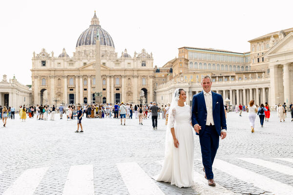 Sposi Novelli couple walking hand in hand with the Vatican in the background